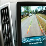 A close-up view shows a screen that shows the view of a backup camera. A street appears on the screen.