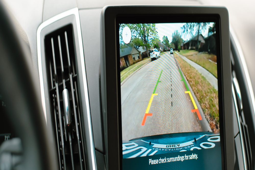 A close-up view shows a screen that shows the view of a backup camera. A street appears on the screen.