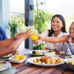 A joyful family enjoys lunch and celebrates with juice on the outdoor patio. They're all smiling and laughing.A joyful family enjoys lunch and celebrates with juice on the outdoor patio. They're all smiling and laughing.