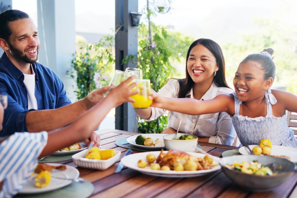 A joyful family enjoys lunch and celebrates with juice on the outdoor patio. They're all smiling and laughing.A joyful family enjoys lunch and celebrates with juice on the outdoor patio. They're all smiling and laughing.